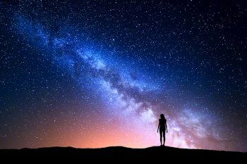 Beautiful Milky Way with standing woman. Colorful landscape with night sky with stars and silhouette of a girl on hill on the background of beautiful galaxy. Blue milky way with yellow light. Space
