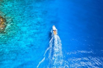 Aerial view of the speed boat in clear blue water at sunset in summer. Top view from drone of fast floating yacht in mediterranean sea. Travel in Oludeniz, Turkey. Tropical landscape with motorboat