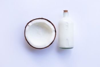 Coconut with bottle of coconut milk on white background.