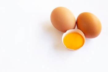 Chicken eggs with yolk on white background.