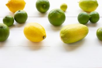 Ripe lemons and limes on white wooden background.
