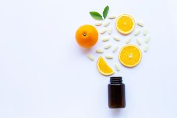 Vitamin C bottle and pills with orange fruit on white background. Copy space