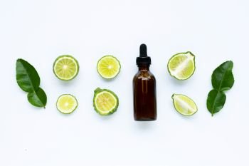 Bottle of essential oil with fresh kaffir lime or bergamot fruit isolated on white 