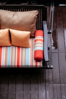 Porch swing with colourful pillows and cushions on wooden balcony top view shot