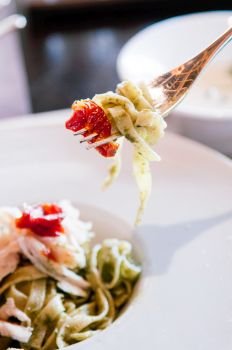 CLose up shot of Linguine Pasta with Pesto Sauce, sundried tomato on fork. Italian Cuisine.