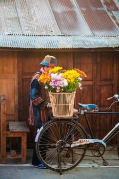 Vintage bicycle with basket full of flowers and local asian woman