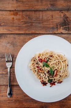 Italian Spaghetti pasta bacon with dried spicy chilli on white plate on the wood table from top view