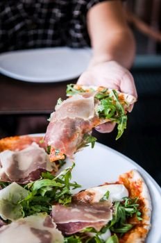 close up shot of italian pizza slice pamaham arugula and margarita sauce in female hand
