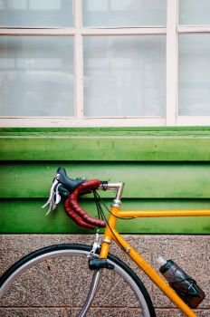 A Yellow Road bicycles parking against green wooden wall.