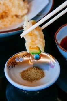 Premium Japanese mix vegetable and avocado tempura picked with chopstick and dip into salt - close up food shot