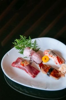 Premium mix sushi on white plate, Foie Gras sushi, Otoro sushi, Wagyu sushi, salmon sushi - Dark background warm tone image