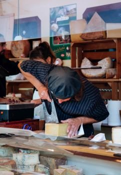 SEP 28, 2013 Bern, Switzerland - A man cutting big chunk piece of cheese in swiss cheese shop