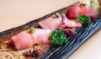 Fresh beautiful pieces of Japanese Otoro tuna sushi on craft ceramic plate, close up shot