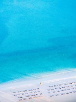 Aerial view of White Sand beach turqouise blue sea with beach beds and guard tower - Abu Dhabi nature landscape