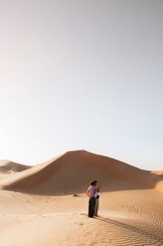 FEB 2, 2015 Abu Dhabi, UAE - European tourists enjoy exotic sand dune scenery in Al Wathba desert under evening light with clear sky. Vase Landscape of Dubai - Abu Dhabi route.