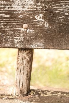Closeup detail of a weathered and natural faded rural wooden bench neglected in the countryside, with a rustic and vintage style.. Closeup detail of a weathered and natural faded rural wooden bench neglected in the countryside, with a rustic and vintage style