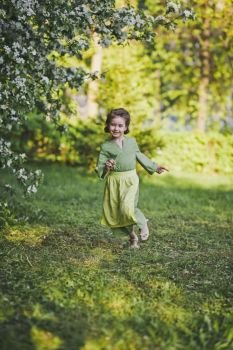 A child running around the green garden.. Happy girl running in the garden 8355.