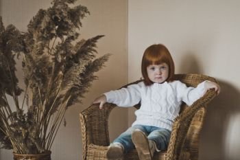 Portrait of a little girl in the white sweater.. Child with red hair in a white sweater 4407.