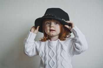 A child with red hair in a white sweater and hat.. Portrait of a child in a white sweater 4414.