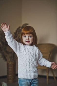 A child with red hair in a white sweater.. Portrait of a little girl in a white sweater 4406.