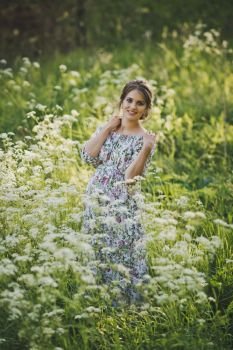 Simple female beauty on a glade of flowers of the kupyr forest.. Portrait of a happy pregnant woman in a clearing of white flowers of a for