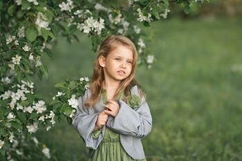 The child stands near a flowering cherry Bush.. Portrait of a little girl in spring in flowering trees 1804.