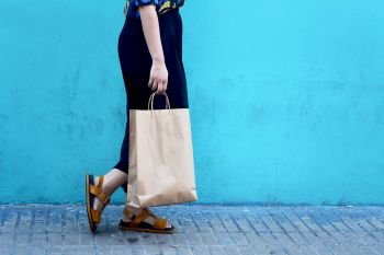 Close up view of young woman walking with shopping bags against a colorful urban wall. Shopping concept
