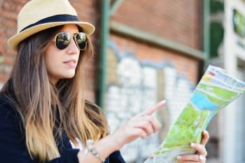 Portrait of a young beautiful tourist looking at a map. Tourism concept. Outdoors.