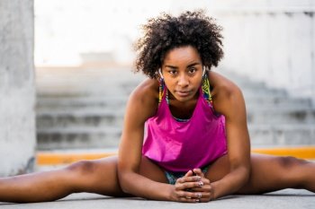 Portrait of afro athlete woman stretching legs before exercise outdoors. Sport and healthy lifestyle.. Afro athlete woman stretching legs before exercise.