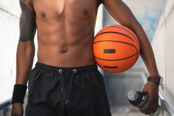 Closeup of an athletic man holding a basketball ball after training outdoors. Sport and healthy lifestyle.