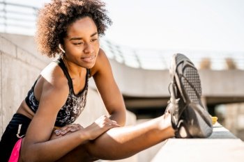 Portrait of afro athlete woman stretching legs before exercise outdoors. Sport and healthy lifestyle.