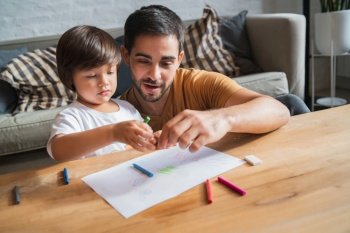 Little boy and his father spending time together drawing at home. 