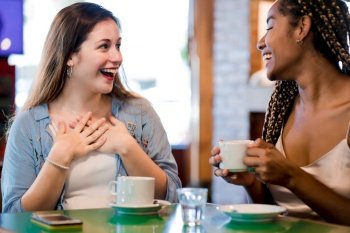 Two female friends enjoying time together while drinking a cup of coffee at a coffee shop. Friends concept.