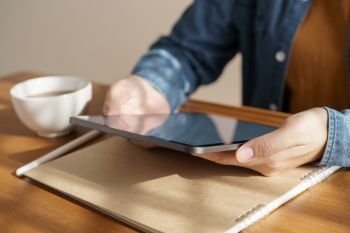 Asian woman’s hands are using tablet on wooden table