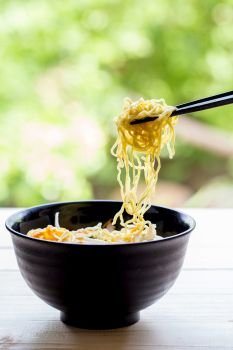 Chinese egg noodles with chopsticks on wood table
