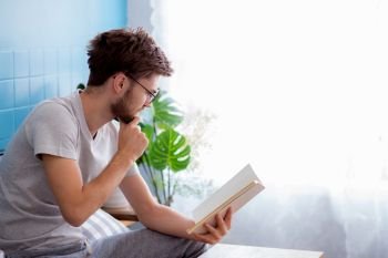 Young man wear glasses reading book on sofa in the living room with education concept