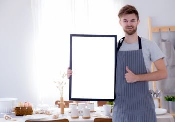 handsome chef showing blank empty board menu sign for restaurant menu or recipe with kitchen background.