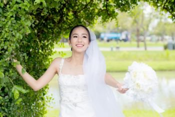 beautiful young woman on wedding day in white dress in the tree wall. Female portrait in the park - Selective focus
