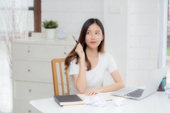 Young asian woman confident working at home with laptop computer and thinking idea for planning, freelance happy girl excited and success using notebook thoughtful and writing, business concept.