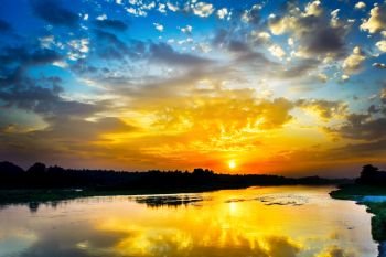 Beautiful lake landscape with vivid sunrise on the cloudy sky. River landscape. Beautiful summer landscape with golden sunset.