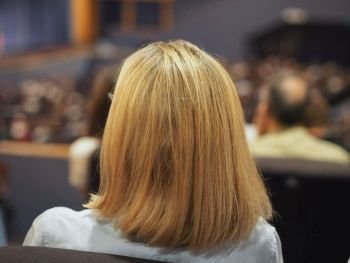 Unrecognisable woman attending an event, seen from behind. Unrecognisable woman at event