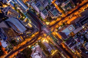 Aerial view of Sathorn intersection or junction with cars traffic, Bangkok Downtown, Thailand. Financial district and business area. Smart urban city technology. Skyscraper and buildings at night.