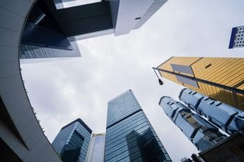 Looking up to high-rise buildings, skyscrapers, architectures in smart city for business and technology background in Hong Kong City with blue sky