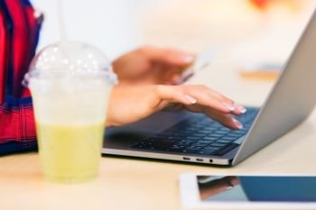Closeup view of young woman working on her laptop or notebook in the cafe