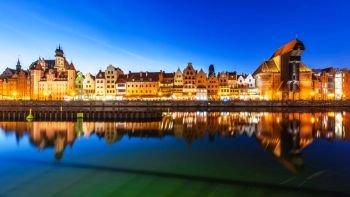 Scenic night panorama of the Old Town pier architecture of Gdansk, Poland at the Motlawa River harbor embankment with medieval port crane and historical ships