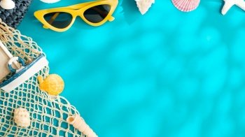 sunny day summer beach sea accessories,sunglasses,brown hat and seashell over blue background banner with sunlight