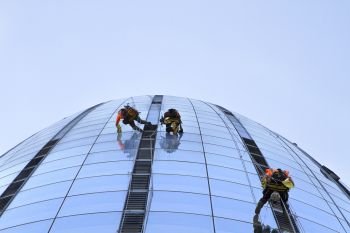 Window cleaners working on a high rise building. Low angle view