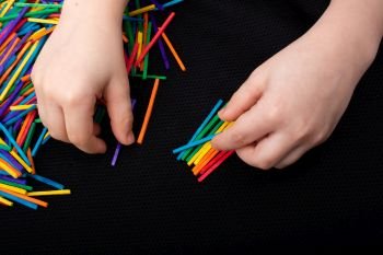 Kid playing with coloured wooden  sticks for creativity on white background