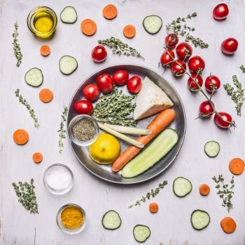 Tomatoes on a branch of thyme herb seasoning lemon cucumbers and tomatoes carrots in a pan with vegetables laid out around on wooden rustic background top view