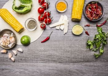 ingredients for burritos with tomato, pepper, spicy chili, corn, cheese and garlic border with space for text on grey wooden rustic background top view close up